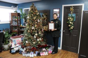 Nancy Jones, owner of New Attitudes Day Spa in Bryson City, started Shoes for Steps. She's pictured with donations this year by the tree in her shop.