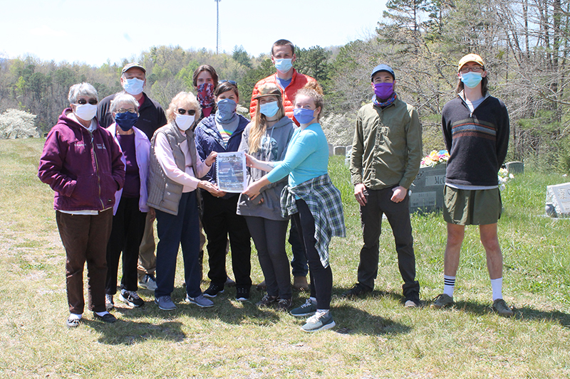 Photo by Jessica Webb Volunteers with Southwestern Community College Outdoor Leadership Club spent time last Thursday getting the Lauada Cemetery ready for summer. Above, club president Makenna Samuel presents Lauada Cemetery Association President Christine Proctor with one of the 100 copies of the cemetery directory SCC made for the association which relies on the sale of the books to help fund cemetery maintenance.