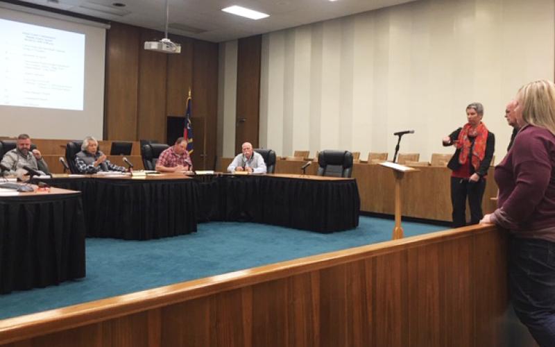 rish Hipgrave, Chair of Coalition for a Safe and Drug Free Swain County, at podium, speaks to the Swain County Board of Commissioners about the plans for a safe syringe drop box. Also standing at right are Health Director, Alison Cochran and Sheriff Curtis Cochran.