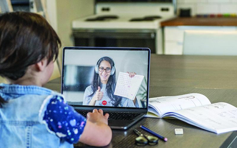 Student learning on a computer with a teacher on the screen