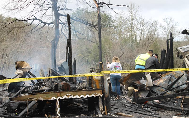 Two residents search for the remains of a few items with a sheriff's investigator
