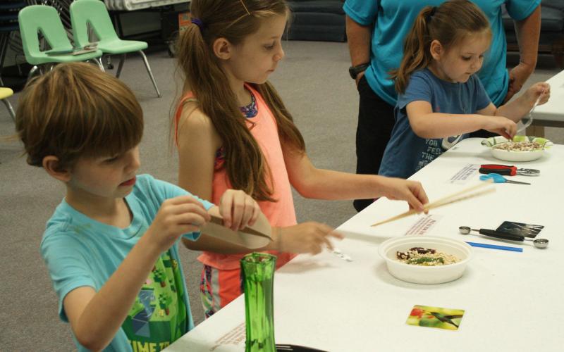 Students work with different tools to get a feel for what different bird beaks are like and how they function during Fill the Bill at the Summer Learning Program at the library.