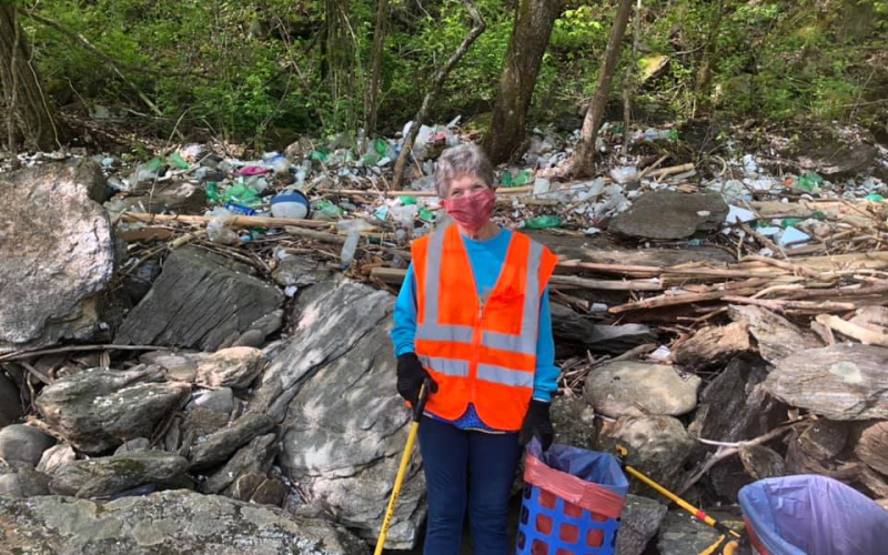 A Swain Clean volunteer in front of a large amount of trash