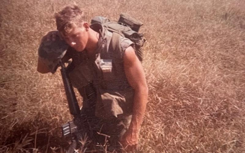 Frank Jones is pictured in wartime in a field in Vietnam.