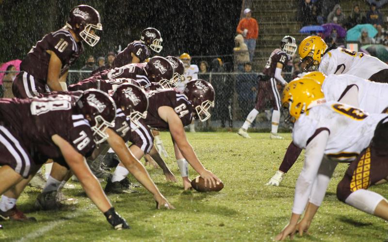 Maroon Devil lineman faceoff against Cherokee defenders in the pouring rain