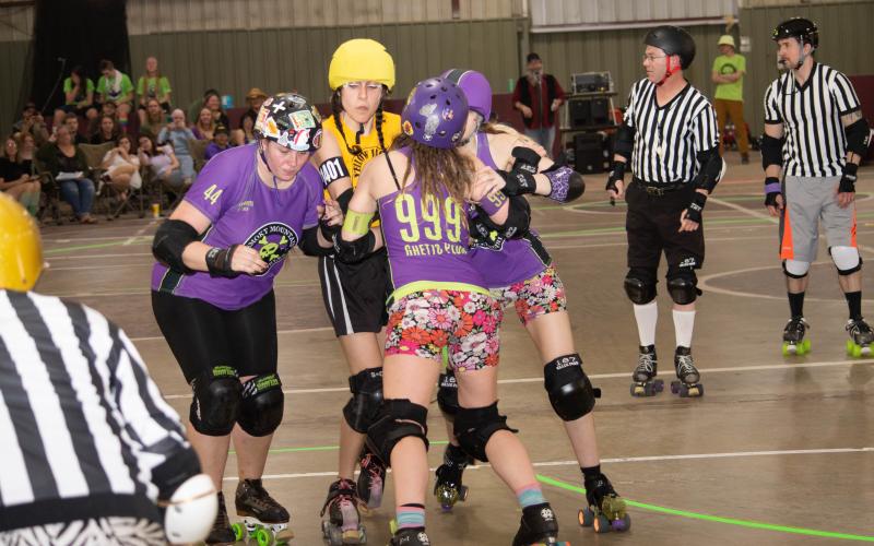 Jackie Bridgers “Ghetto Plum” holds back a jammer with her teammates on Smoky Mountain Roller Girls at a previous home bout. The team will host its next home game Saturday.
