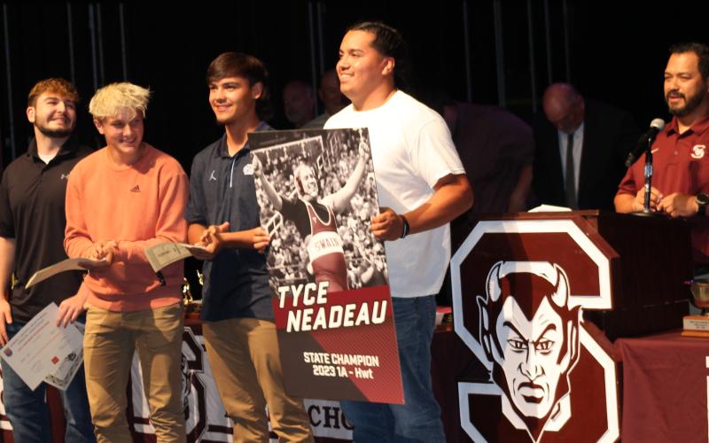 Tyce Neadeau (front) holds up the photo taken of him after winning the heavyweight wrestling champion title.