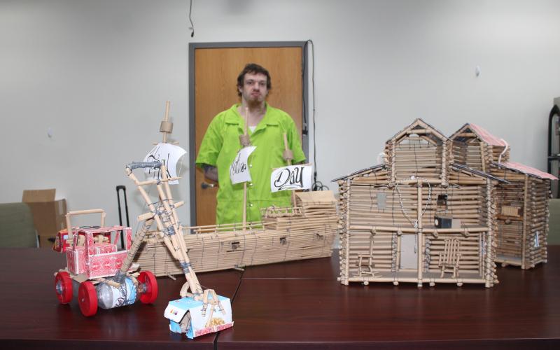 Dustin Dyer is pictured with a toy tractor, sailing ship and two doll houses that he has constructed out of paper lunch bags and other limited materials available to him at the jail.