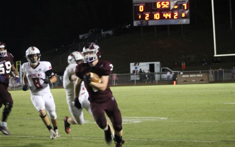 Maroon Devil Josh Collins runs with the ball at the home football game on homecoming night, pursued by several opposing Wildcats.