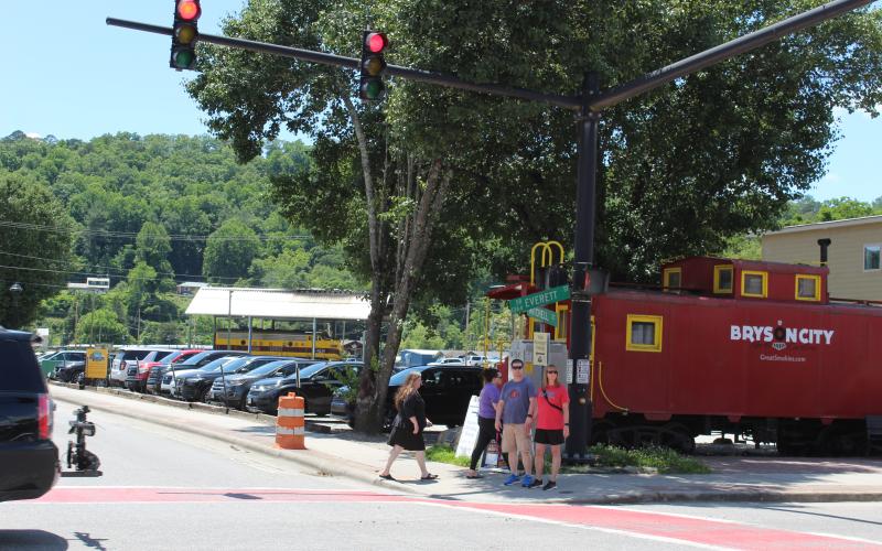 People wait at the crosswalk at Mitchell and Everett streets in front of the red caboose.