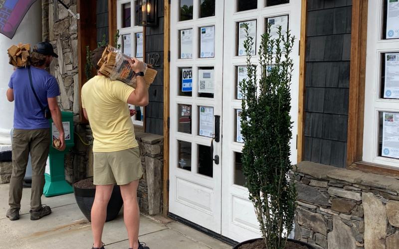 Swain County visitors look at listings posted on the windows and doors at Good Life Real Estate located on Everett Street in downtown Bryson City.