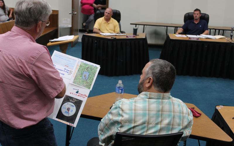 Rep. Mike Clampitt, a resident of Toot Hollow, shows town engineer Nate Bowe a poster with information about his water meter, raising questions about usage.