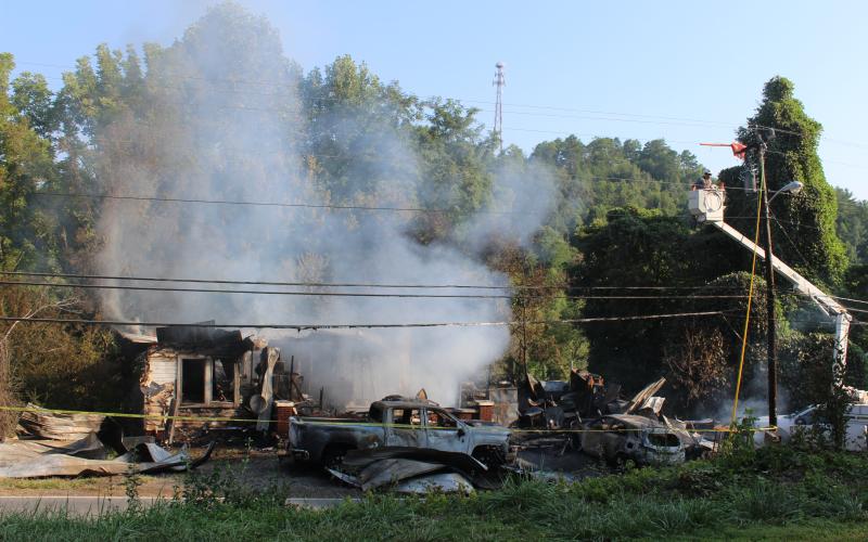 A house fire on Main Street still smolders on Friday morning as a crew from Duke Energy works on the electric lines outside.