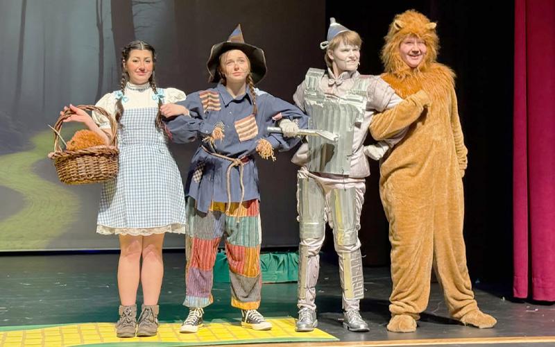 Photo/Rosemary Pearl Moore.  Cassie Fortner as Dorothy, Scout Claxton as Scarecrow, Myles Taylor as Tin Man and Hunter Smith as Cowardly Lion stand arm-in-arm on their way to Oz during a ‘Wizard of Oz’ rehearsal at Swain Arts Center Friday, March 14. Approximately 30 Swain County elementary through high school students were cast in the play.