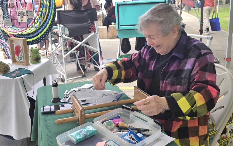 SMT photo/Sara Eisinger.  Joan Stocker designs bracelets with size-11 delicate glass Japanese beads during a demonstration at Heritage Festival in Bryson City Saturday afternoon. She will be back in Bryson City celebrate and sell at Freedom Fest.