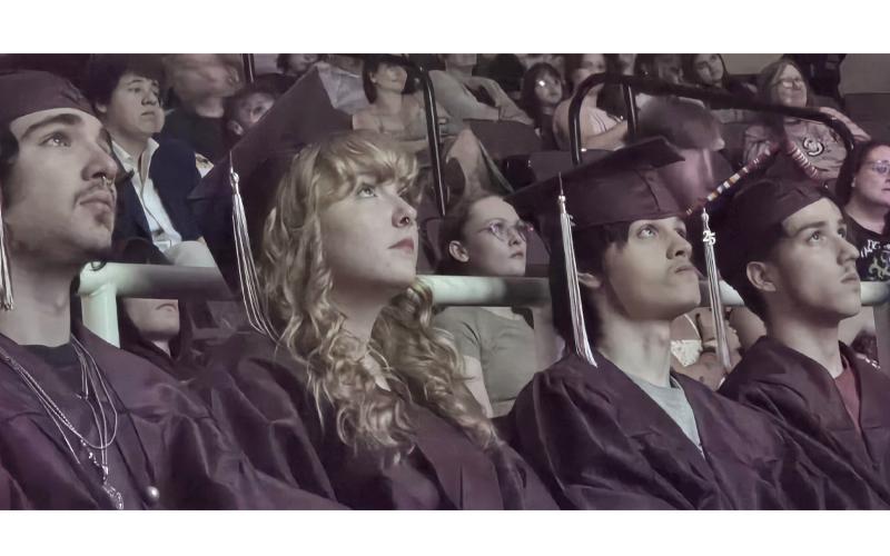 SMT photo/Sara Eisinger.  Landon Blake Coday (left to right), Emma Nicole Houston, Ronald Vincent Arch and Bryan Aguilera watch a slide show of memories and hear from Swain County School staff during a graduation ceremony at Swain Arts Center June 1. Swain Academy graduated 14 students during the school's first graduation ceremony.