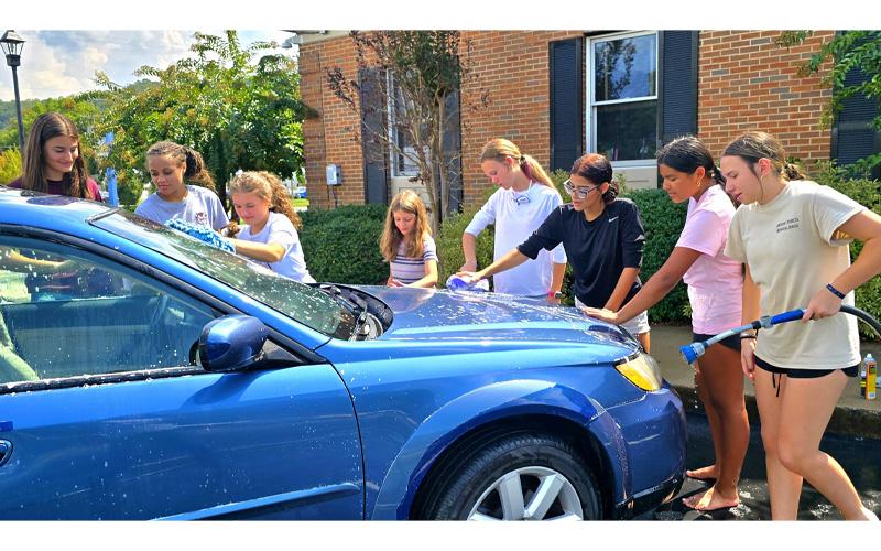 SMT photo/Sara Eisinger.   Addison Blankenship (left to right), Maddie Izquierdo, Caroline Freshour, Claire Freshour, Joylyn Stillman, Julianna Meraz-Quijada, Khloe French and Madison Mashburn wash the car of Ted Duncan, associate pastor at Bryson City First Baptist Church, at United Community in Bryson City Saturday, Sept. 20.
