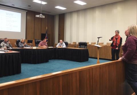 rish Hipgrave, Chair of Coalition for a Safe and Drug Free Swain County, at podium, speaks to the Swain County Board of Commissioners about the plans for a safe syringe drop box. Also standing at right are Health Director, Alison Cochran and Sheriff Curtis Cochran. 