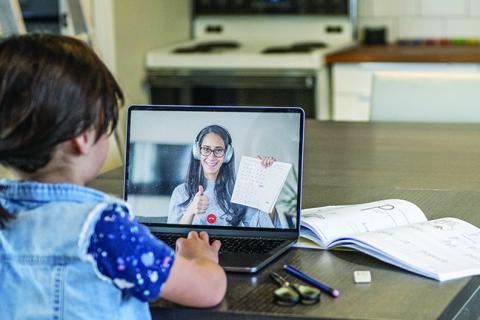 Student learning on a computer with a teacher on the screen