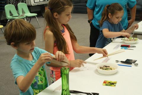 Students work with different tools to get a feel for what different bird beaks are like and how they function during Fill the Bill at the Summer Learning Program at the library.