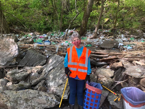 A Swain Clean volunteer in front of a large amount of trash