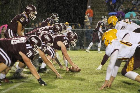 Maroon Devil lineman faceoff against Cherokee defenders in the pouring rain