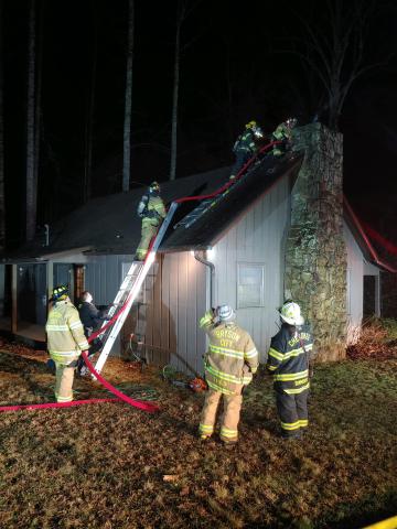 Firefighters climb to the roof of the home on Coopers Creek to put out a fire.