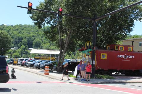 People wait at the crosswalk at Mitchell and Everett streets in front of the red caboose.