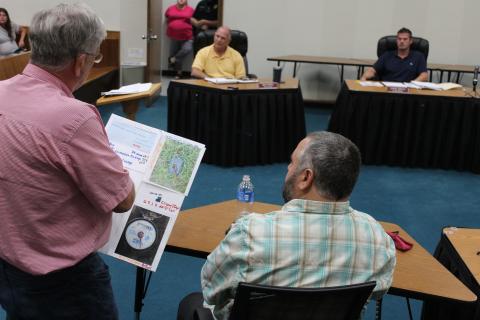 Rep. Mike Clampitt, a resident of Toot Hollow, shows town engineer Nate Bowe a poster with information about his water meter, raising questions about usage. 