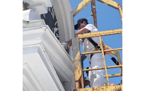Photo/Elliott Pritchard.  Abelino Correa, Huskey’s Paint & Design employee, repainted the Swain County Heritage Museum clock Monday, April 14. He was joined by Miguel Lucas.