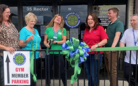 SMT photos/Sara Eisinger.  Michelle Lasky, ambassador at Swain County Chamber of Commerce (left to right), Denene Wolf, gym receptionist, Bibi Pride, gym owner, Monica Brown, chamber president, Ricky Sanford, chamber administrative coordinator, and Anthony Tedesco, personal trainer, gather to cut the yellow ribbon at Bryson City Health and Fitness Saturday, March 29. The chamber currently works with approximately 260 business owners.