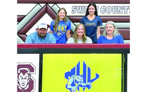 Photo submitted.  Swain County High School senior Faith Woodard (front, center) signs with Mars Hill University, alongside her father, Brandon Woodard, and mother, Michele Woodard, as sisters Molleigh and Haileigh Woodard support her in the background at Swain County High School Tuesday, April 22. Woodard juggles volleyball, basketball, indoor track, softball and outdoor track.
