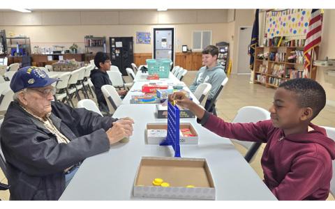 SMT photo/Sara Eisinger.  Swain Middle School student Gabriel Ameh plays Connect Four at the Swain Senior Center with United States Air Force Vet. J.B. Jacobs Thursday, April 10. Sixth, seventh and eighth grade students chose community service clubs, ranging from board games to hunting and fishing, photography and drama.