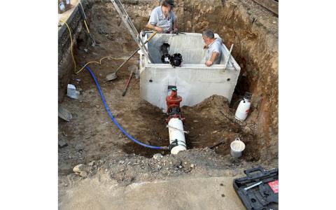 Submitted photo.  City employees Travis McCall (left to right) and Robbie Holloway install a water meter at Deep Creek last week. The town is currently seeking loans from the Local Government Commission to upgrade its meters.