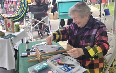 SMT photo/Sara Eisinger.  Joan Stocker designs bracelets with size-11 delicate glass Japanese beads during a demonstration at Heritage Festival in Bryson City Saturday afternoon. She will be back in Bryson City celebrate and sell at Freedom Fest. 