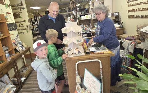 SMT photo/Sara Eisinger.  Molly Shaw, The Wild Fern owner, browses through stickers with “Papahoney Mike” aka grandpa and his grandkids Saturday, May 24. Other customers flocked inside to browse Solmate Socks and other American made products. 