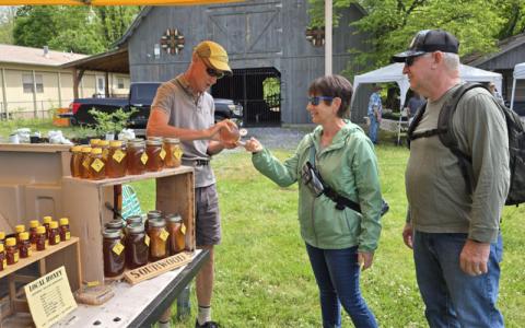 SMT photo/Sara Eisinger. Jim Parham, beekeeper at Smoky Mountain Honey, sells to Mark and Shawn Johnson at the Smoky Mountain Farmers and Artisans Market Friday, May 2. The market will continue through the last Friday in October.