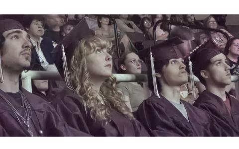 SMT photo/Sara Eisinger.  Landon Blake Coday (left to right), Emma Nicole Houston, Ronald Vincent Arch and Bryan Aguilera watch a slide show of memories and hear from Swain County School staff during a graduation ceremony at Swain Arts Center June 1. Swain Academy graduated 14 students during the school's first graduation ceremony.