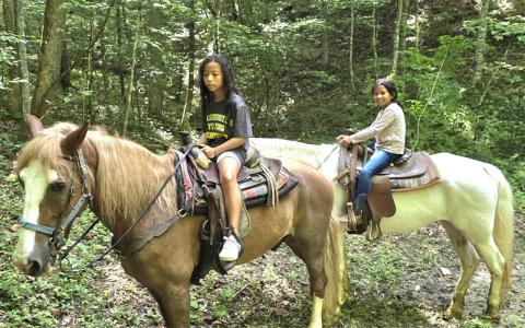 SMT photo/Sara Eisinger.  Lim sisters Uhura, 11, and Cosima, 8, of Washington, D.C. bravely ride through the mountainous Nantahala National Forest with their mother and Nantahala Village Riding Stables guide Saturday afternoon. The girls visit the riding stables when vacationing in Western North Carolina every year.