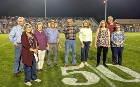 Mike Clapsaddle (left to right), Janet Clapsaddle, Lynn James, Duane James, Bill Watson, Sherry Jenkins Brown, Beth Pedersen, Nick Lambert and Dottie Nelson on the Maroon Devils football field 50-yard-line Sept. 5. 