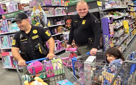 SMT photo/Sara Eisinger. Swain County Sheriff’s Office deputies Tony Reynaldo and Chase Hughes eagerly help local students shop for Christmas during the county’s first Shop with a Cop event at Walmart in Franklin Dec. 8.
