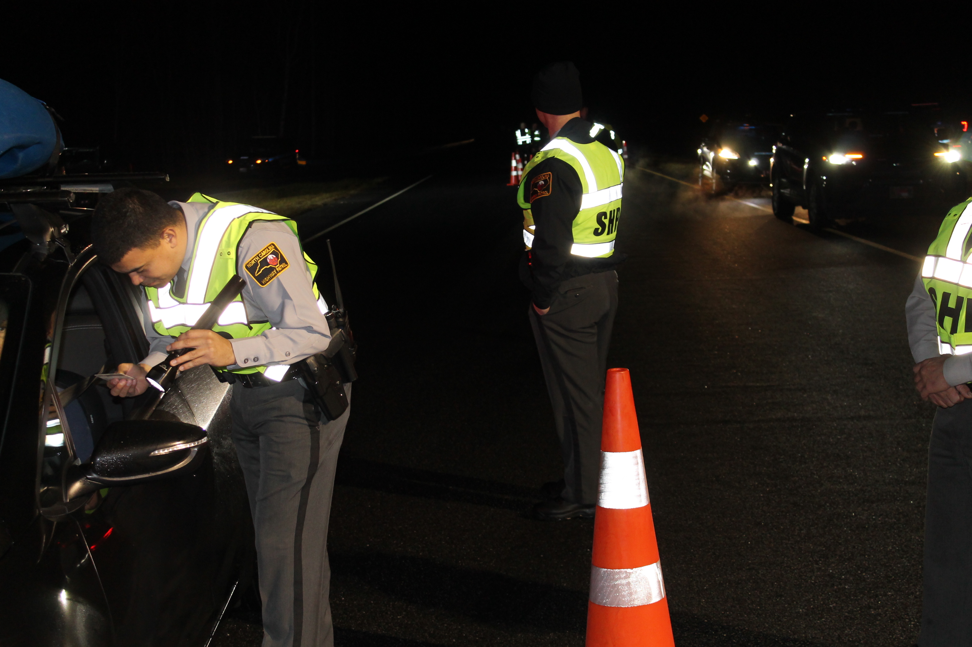 North Carolina Highway Patrol Trooper Jones, of Graham County, checks a driver's license during the multi-agency DWI checkpoint held on New Year' Eve near the Swain-Graham county line. 