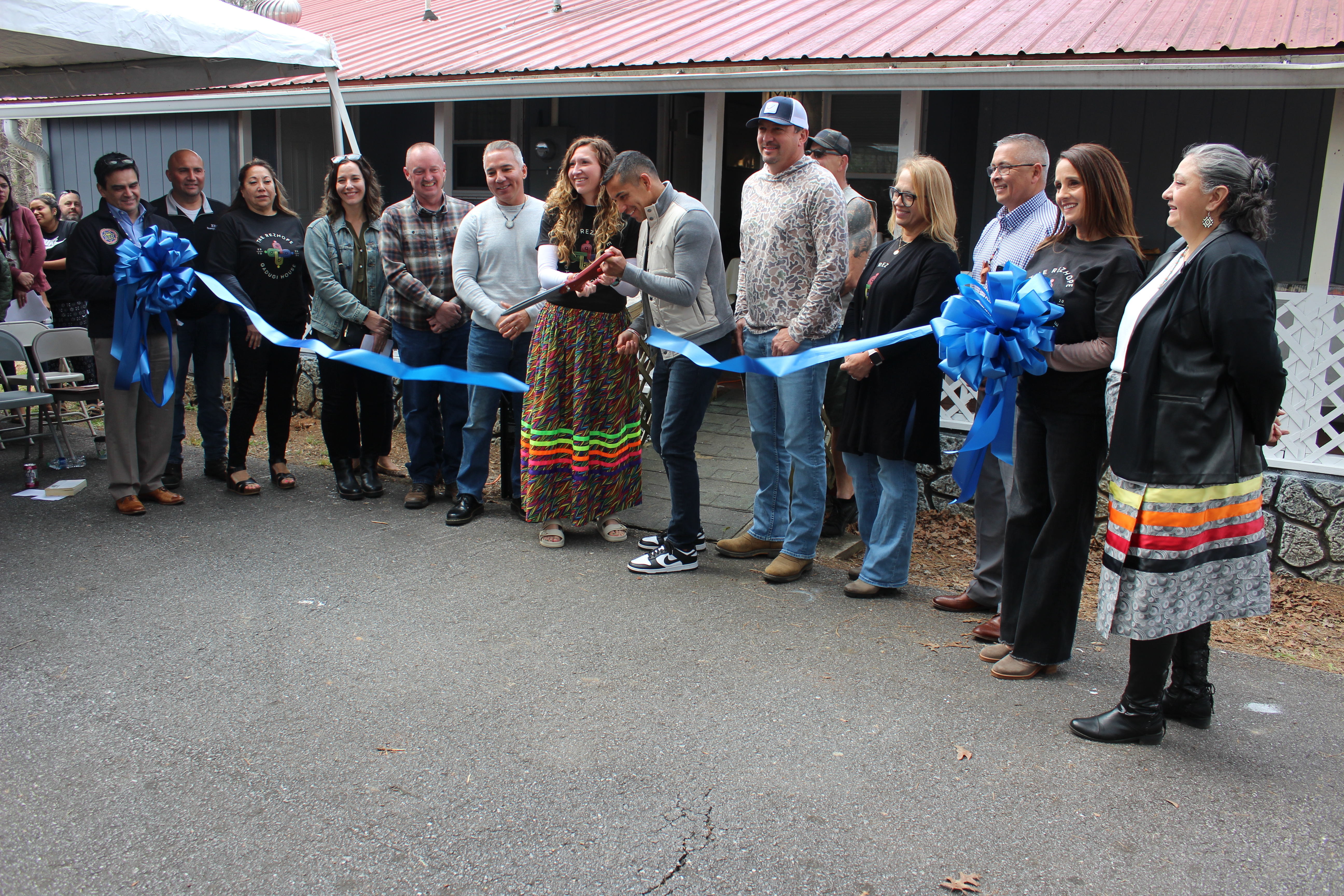 RezHOPE founder Kallup McCoy II and executive director Katelynn Ledford-McCoy are surrounded by board members and tribal leaders for a ribbon cutting ceremony for The Gadugi House, a men’s transitional living house.