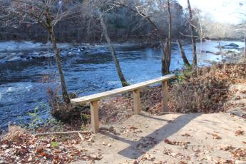 Erosion is obvious at this bench overlooking the river where the earth falls away at the edge of the bench.
