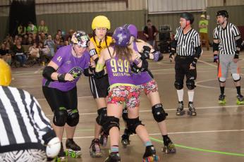Jackie Bridgers “Ghetto Plum” holds back a jammer with her teammates on Smoky Mountain Roller Girls at a previous home bout. The team will host its next home game Saturday.
