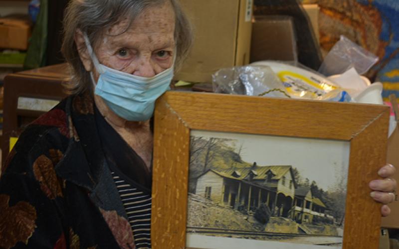 Juanita Lester holds a framed picture of her childhood home that was in the Bushnell community, one of several lost to the formation of Fontana Lake.