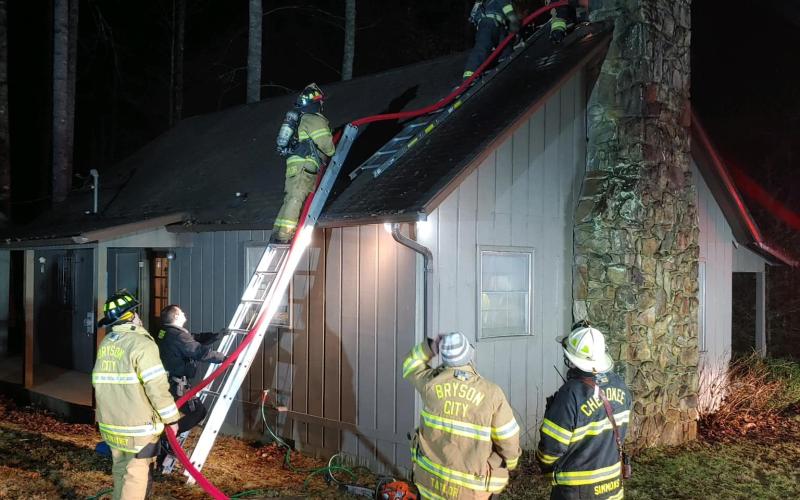 Firefighters climb to the roof of the home on Coopers Creek to put out a fire.