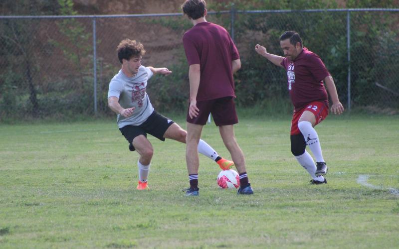 Landon Matz (from left) tussles with opponents Booth Bassett and Antonio Barrera during the frenetic fray of the alumni men’s soccer game Aug. 4.