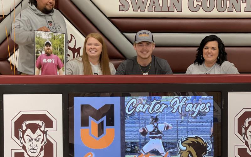 Swain County High School is proud to announce that senior Carter Hayes has signed to continue his baseball career at Milligan University. In his junior season Carter was the Smoky Mountain Conference Player of the Year. He compiled a.440 batting average to go with 23 RBI and an OPS of 1.282 with 24 walks. Hayes was outstanding behind the plate for the Devils, catching every game and flashing gold glove caliber defense. Pictured, Carter (center) is surrounded by his family as he signs.