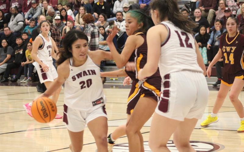Lady Devils senior Triniti Littlejohn (from left) and sophomore Carley Teesateskie grapple with a Lady Braves athlete over the ball at the game Friday, Jan. 5.